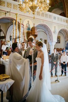 a bride and groom standing in front of the alter at a wedding ceremony with other people looking on