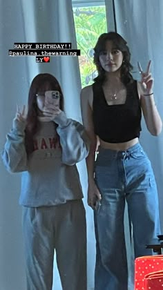 two women standing next to each other in front of a window with the words happy birthday written on it