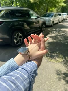 a person holding their hand out in front of parked cars