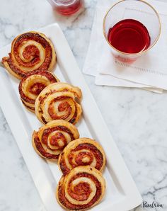 several pastries on a white plate next to a glass of wine and napkins