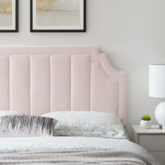 a pink headboard in a bedroom with two framed pictures above the bed and nightstands