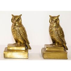 two gold owl figurines sitting on top of bookends in the shape of books