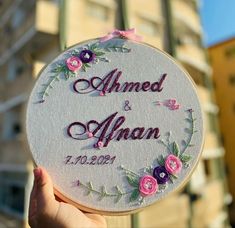 a person holding up a wedding ornament in front of a building with flowers on it