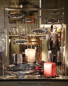 a mannequin is standing in front of a display case with suitcases and other items