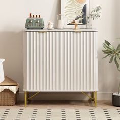 a white cabinet sitting next to a potted plant