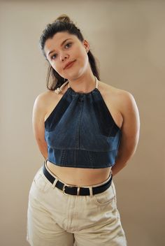 a woman with her hands on her hips wearing white pants and a denim crop top