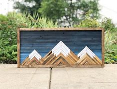 a wooden sign with mountains painted on it