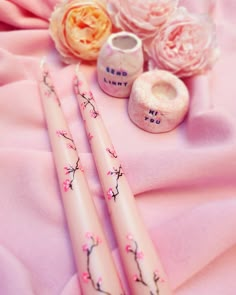 two pink pens sitting on top of a pink blanket next to flowers and vases