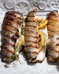 grilled fish with lemons and herbs on a white platter, ready to be eaten