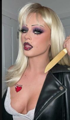 a woman with long blonde hair and makeup is holding a knife in her right hand