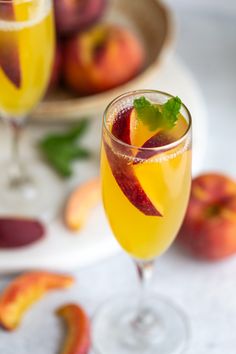 two glasses filled with fruit and garnish sitting on top of a white table