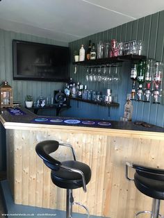 a bar with two stools in front of it and a television on the wall