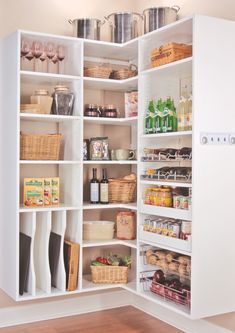 an organized pantry with white shelving and lots of food in the corner on wooden flooring