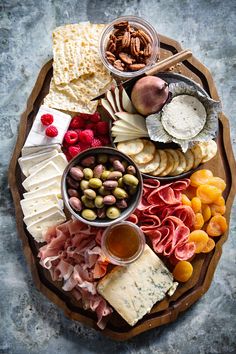 an assortment of cheeses, meats and nuts on a platter with crackers