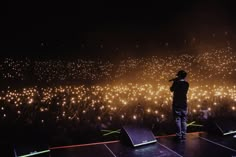 a man standing on top of a stage next to a large group of people at night