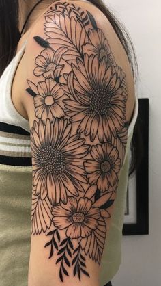 a woman's arm with black and white flowers on the back of her shoulder