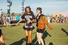 two women walking in the grass at a music festival