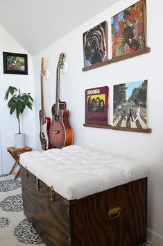 a room with guitars and pictures on the wall, including a bench in front of a guitar case