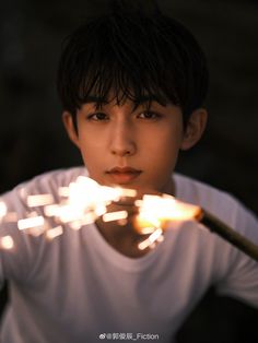 a young boy holding a stick with fire coming out of it