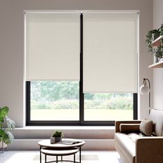 a living room with a couch, coffee table and large window covered in white blinds