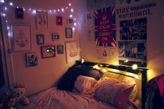 a bedroom with lights and pictures on the wall above the bed, along with stuffed animals