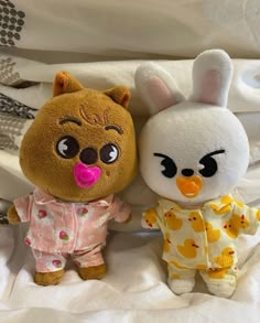 two stuffed animals sitting next to each other on a bed