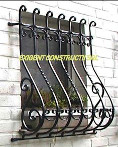 an iron window grill on the side of a white brick building with potted plants in it