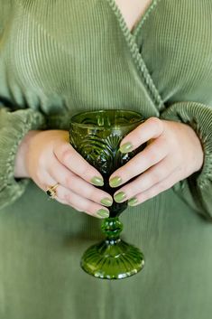 a woman holding a green wine glass in her hands