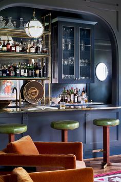 a bar with lots of bottles and stools in front of an arch doorway that leads to another room