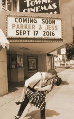 a man and woman kissing in front of a movie theater