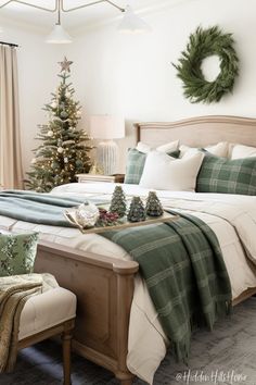 a bedroom decorated for christmas with green and white decorations on the bed, plaid throw pillows, wreaths and other holiday decor