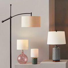 three lamps are sitting on a shelf next to each other and one lamp has a white shade