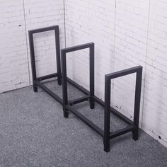 two black metal frames against a white brick wall in an empty room with grey carpet