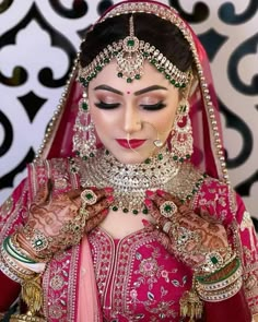 a woman in a red and gold bridal outfit with her hands on her chest