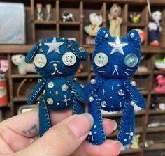 two small blue teddy bears sitting next to each other in front of a shelf filled with toys