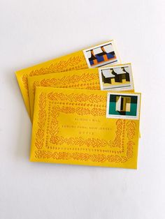 three yellow envelopes with stamps on them sitting next to each other and one has an image of a dog