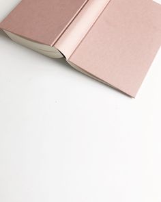 an open pink book on a white surface