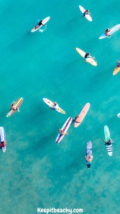 an aerial view of several surfers in the ocean with their surfboards and boards