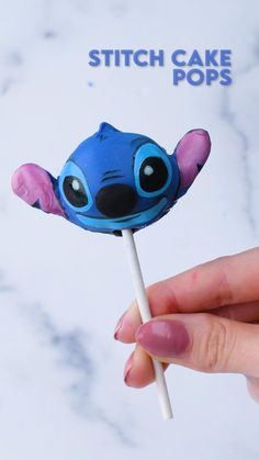 a hand holding a blue and pink stitch cake pops with the words stitch cake pops on it