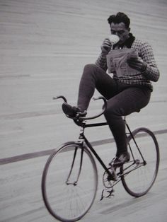 a man riding a bike while drinking from a cup