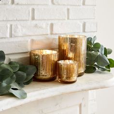 three gold candles sitting on top of a white mantle