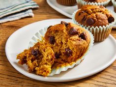 two muffins sitting on top of a white plate next to another muffin