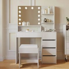 a white vanity with lights on it in a room next to a dresser and mirror