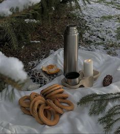 hot dogs and pretzels sitting on a blanket in the snow next to a candle