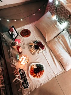 a bed that has some food on it and lights in the room around it,