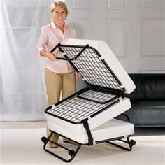 a woman standing next to a black and white couch with two folding chairs on it