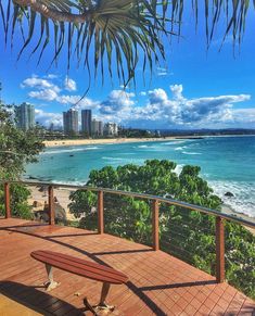 a wooden bench sitting on top of a deck next to the ocean