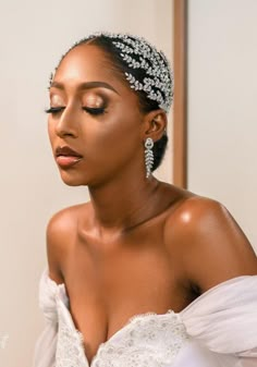 a woman in a white dress wearing a headpiece with pearls and beads on it