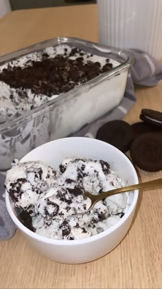 a bowl filled with ice cream next to an oreo cookie on top of a wooden table