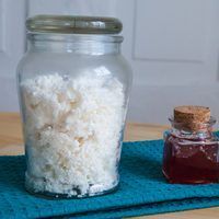 a jar filled with white rice next to a bottle of honey on top of a blue towel